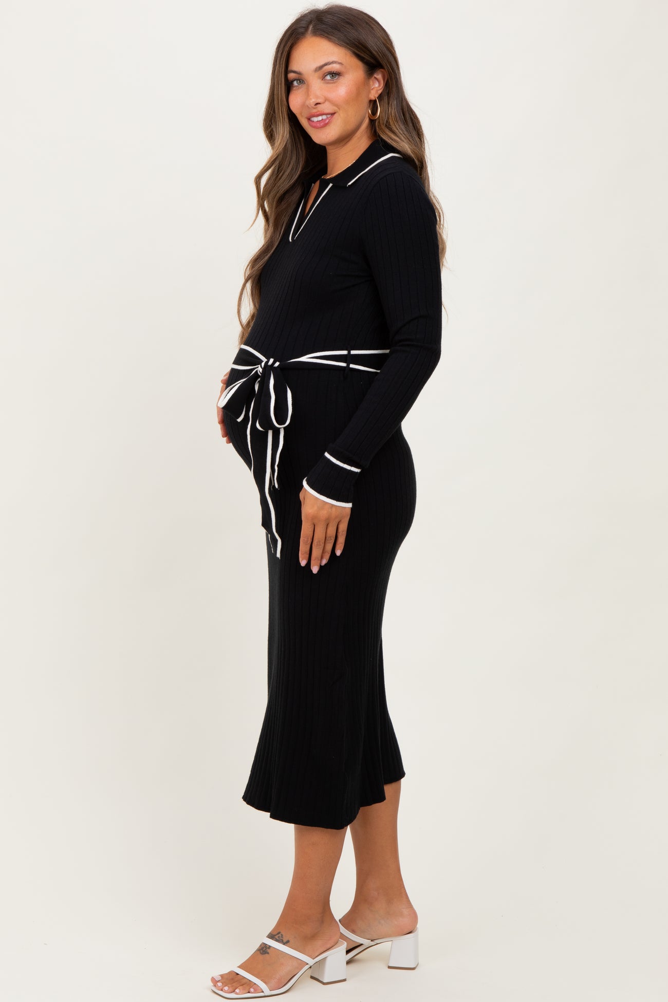 woman wearing a black ribbed maternity dress with white collar and tie waist, showcasing her baby bump