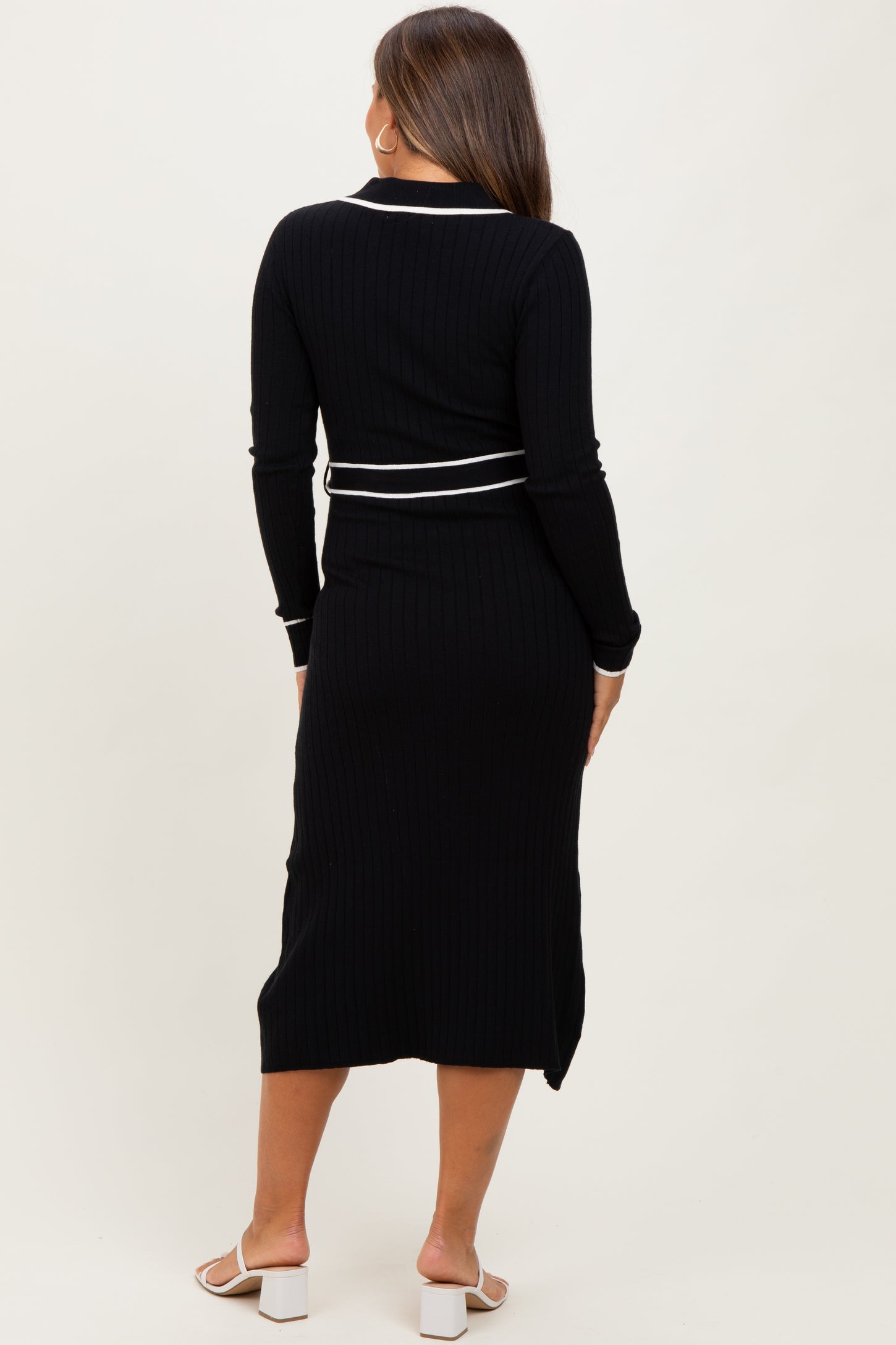woman wearing a black ribbed maternity dress with white trim and long sleeves, showing a baby bump from the back