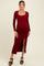 woman wearing a red ribbed maternity dress with long sleeves and a side slit, showcasing her baby bump