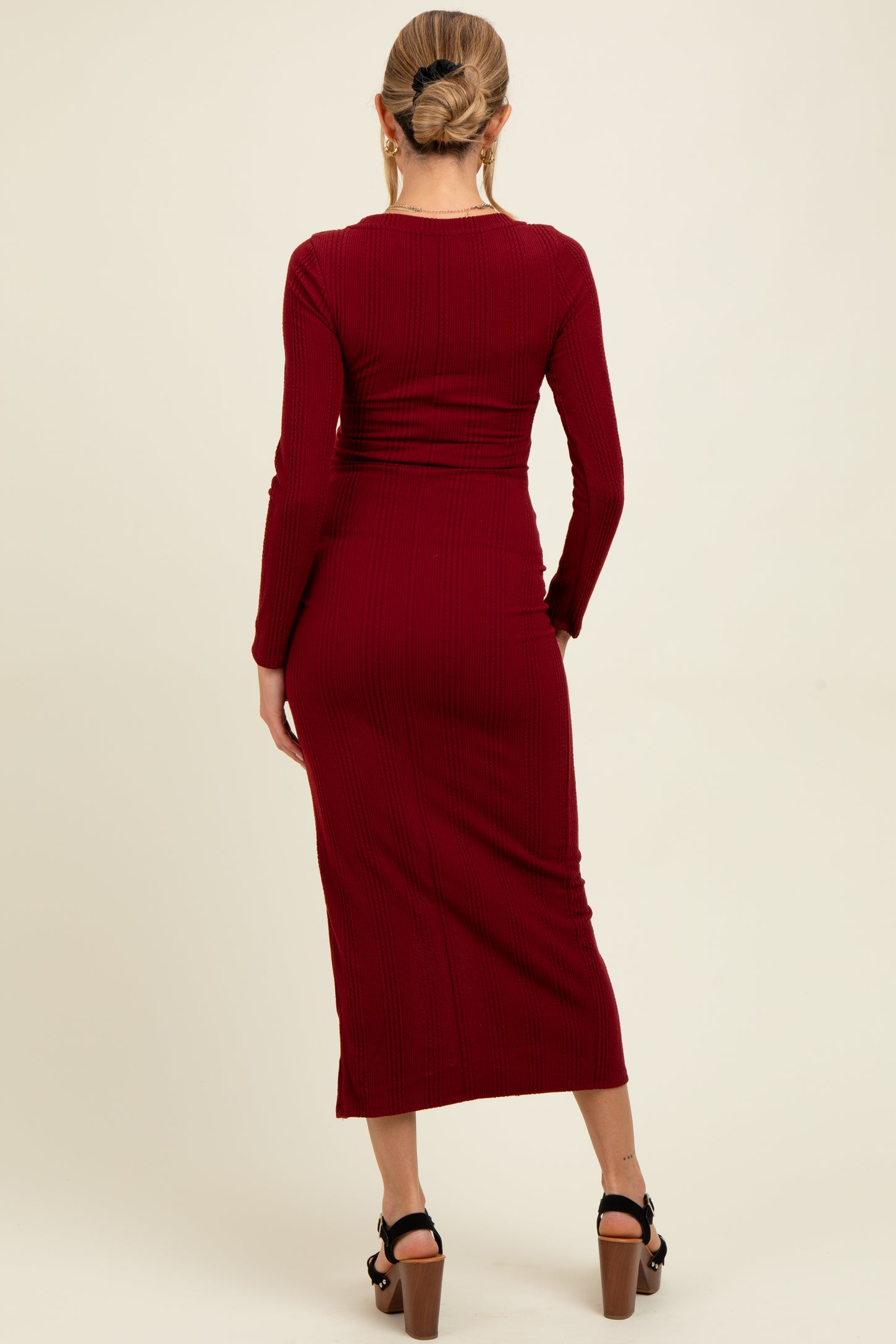 woman wearing a ribbed burgundy maternity dress with long sleeves and a fitted silhouette