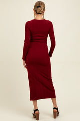 woman wearing a ribbed burgundy maternity dress with long sleeves and a fitted silhouette