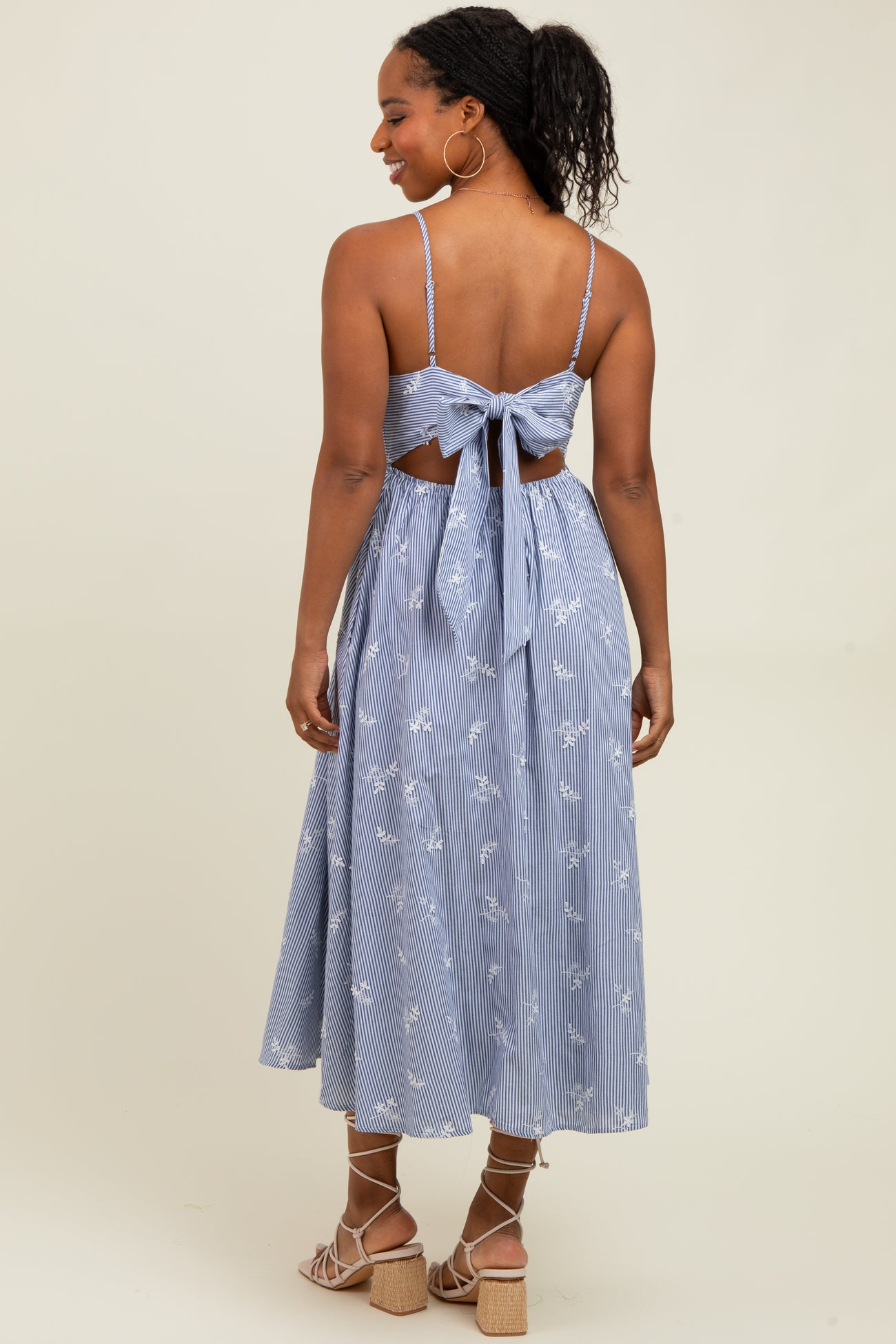 woman wearing a blue and white striped midi dress with a back tie detail and floral embroidery