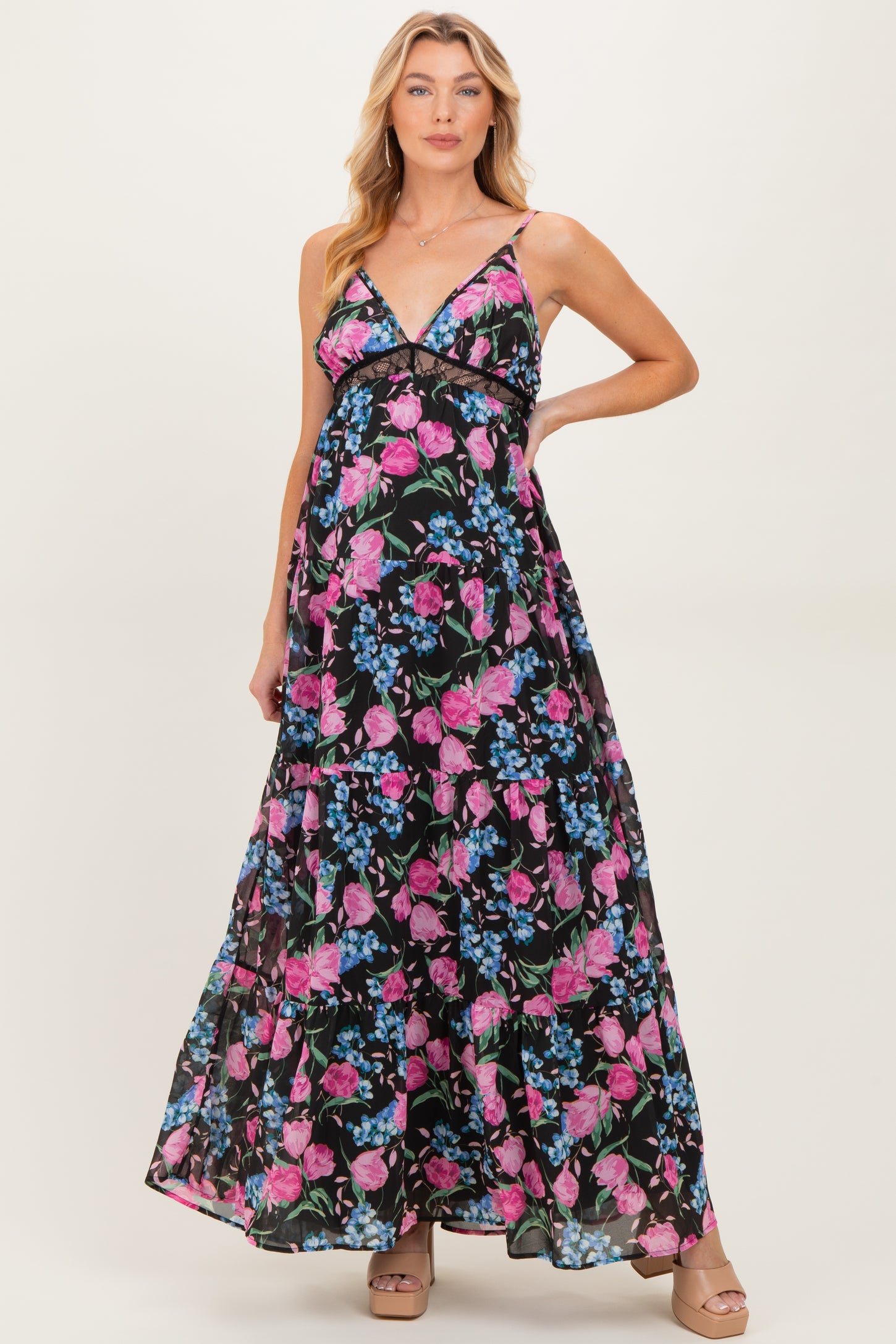 woman wearing a black floral maternity maxi dress with pink and blue flowers, featuring a deep V neckline and spaghetti straps
