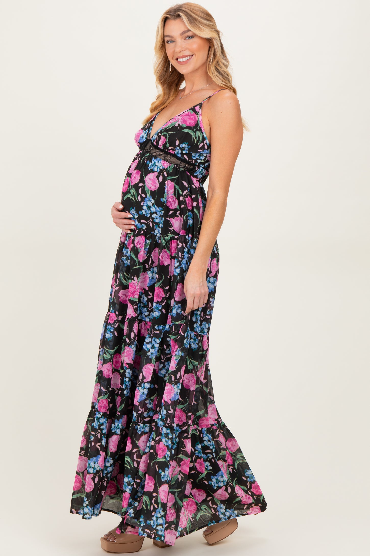 woman wearing a floral print maternity maxi dress and holding her baby bump