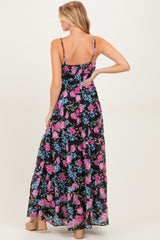 woman wearing a floral maternity maxi dress with a black background and adjustable straps, showing off her baby bump from the back