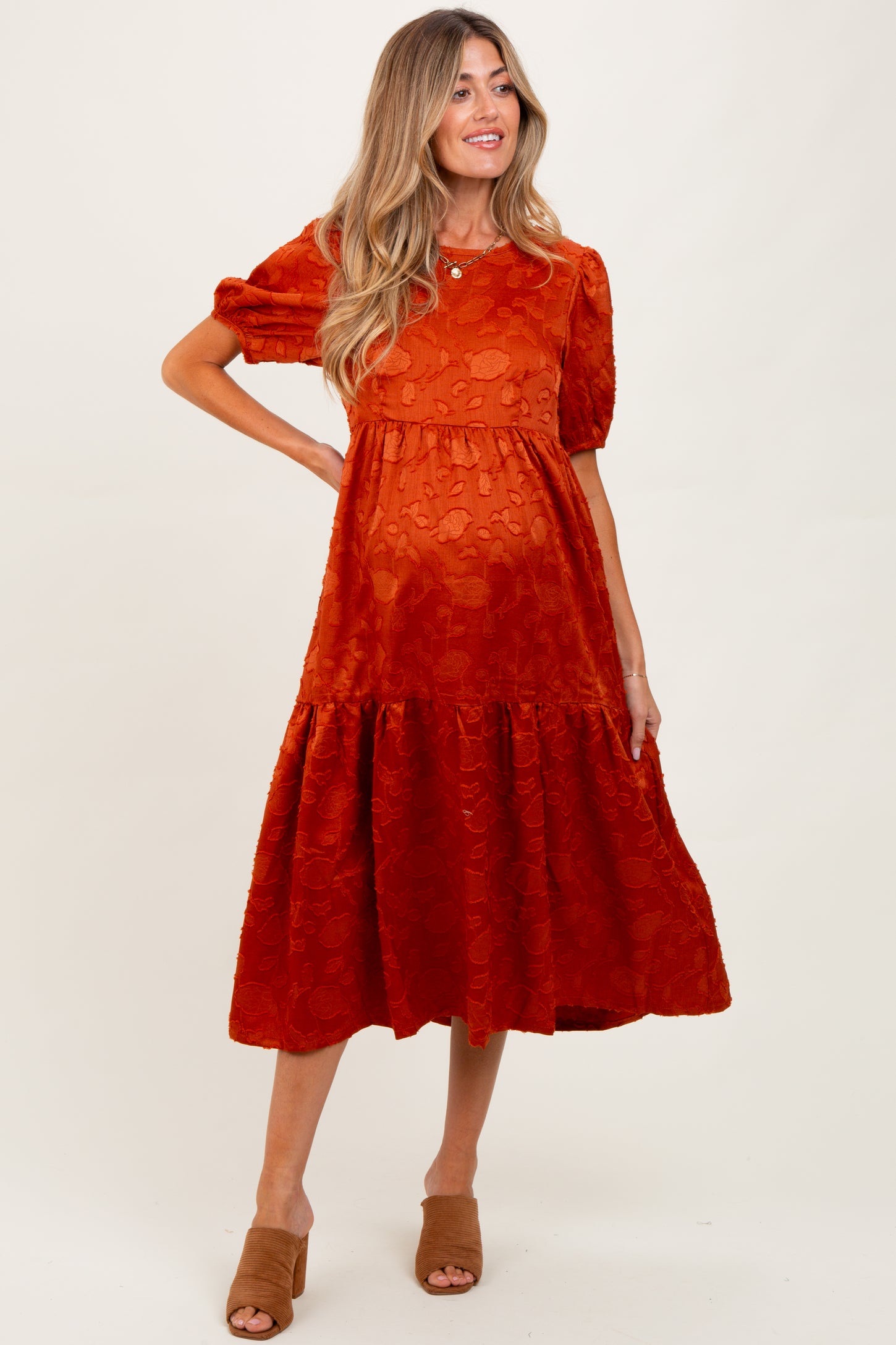 woman wearing an orange maternity dress with short puff sleeves and a tiered skirt, showing her baby bump