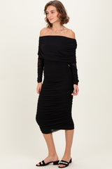woman wearing a black off-the-shoulder ruched dress with long sleeves and styled with black slide sandals