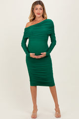 woman wearing a green one-shoulder ruched maternity dress and holding her baby bump
