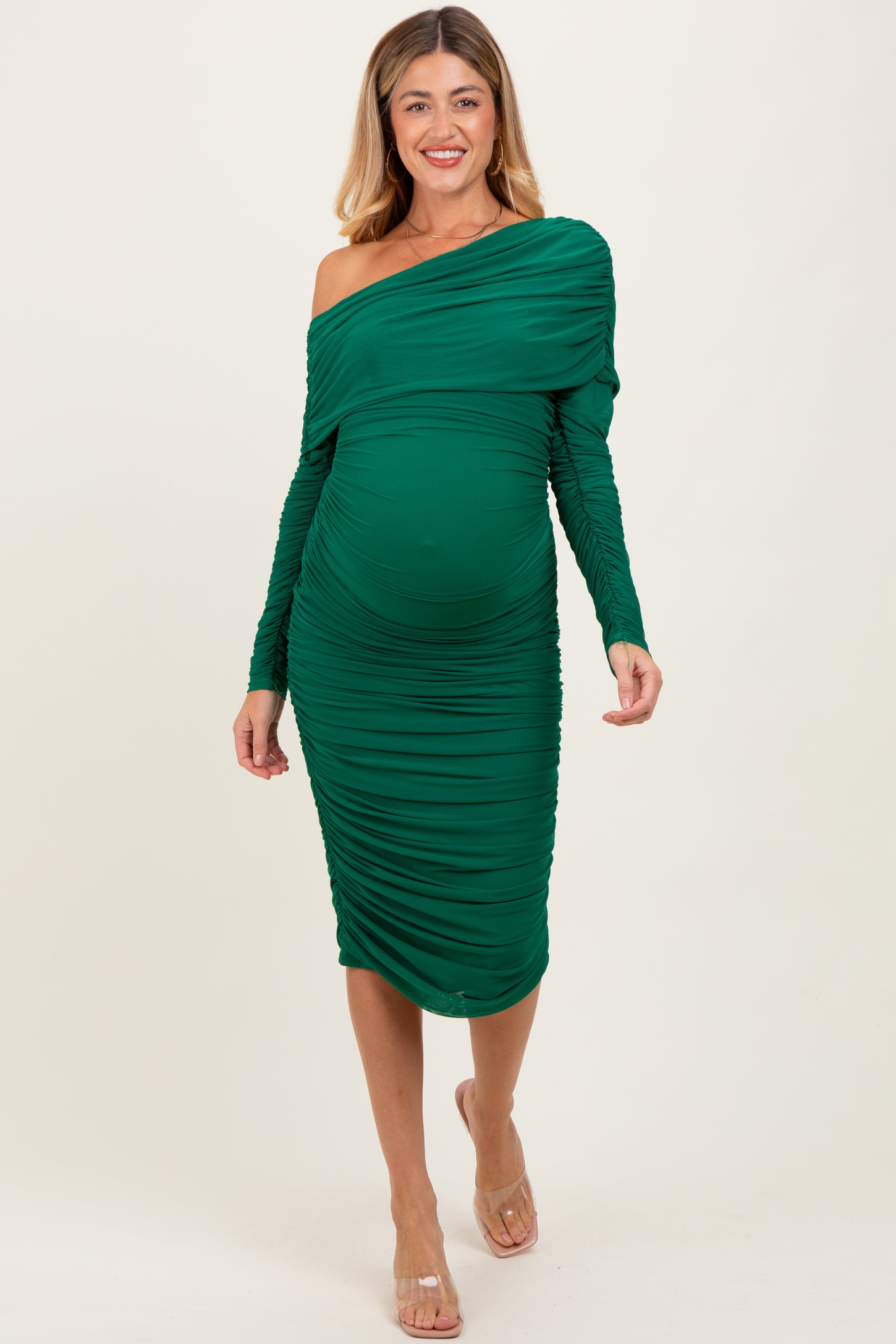 woman wearing a green off-shoulder maternity dress with ruching and a visible baby bump
