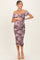 woman wearing a purple floral off-shoulder maternity dress and holding her baby bump