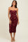 woman wearing a burgundy strapless midi dress with ruched detailing and a fitted silhouette