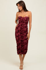 woman wearing a burgundy strapless bodycon dress with ruching details and a straight neckline