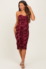 woman wearing a burgundy strapless maternity dress with ruching details and a fitted silhouette