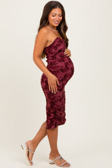 woman wearing a burgundy strapless maternity dress with ruching and a visible baby bump