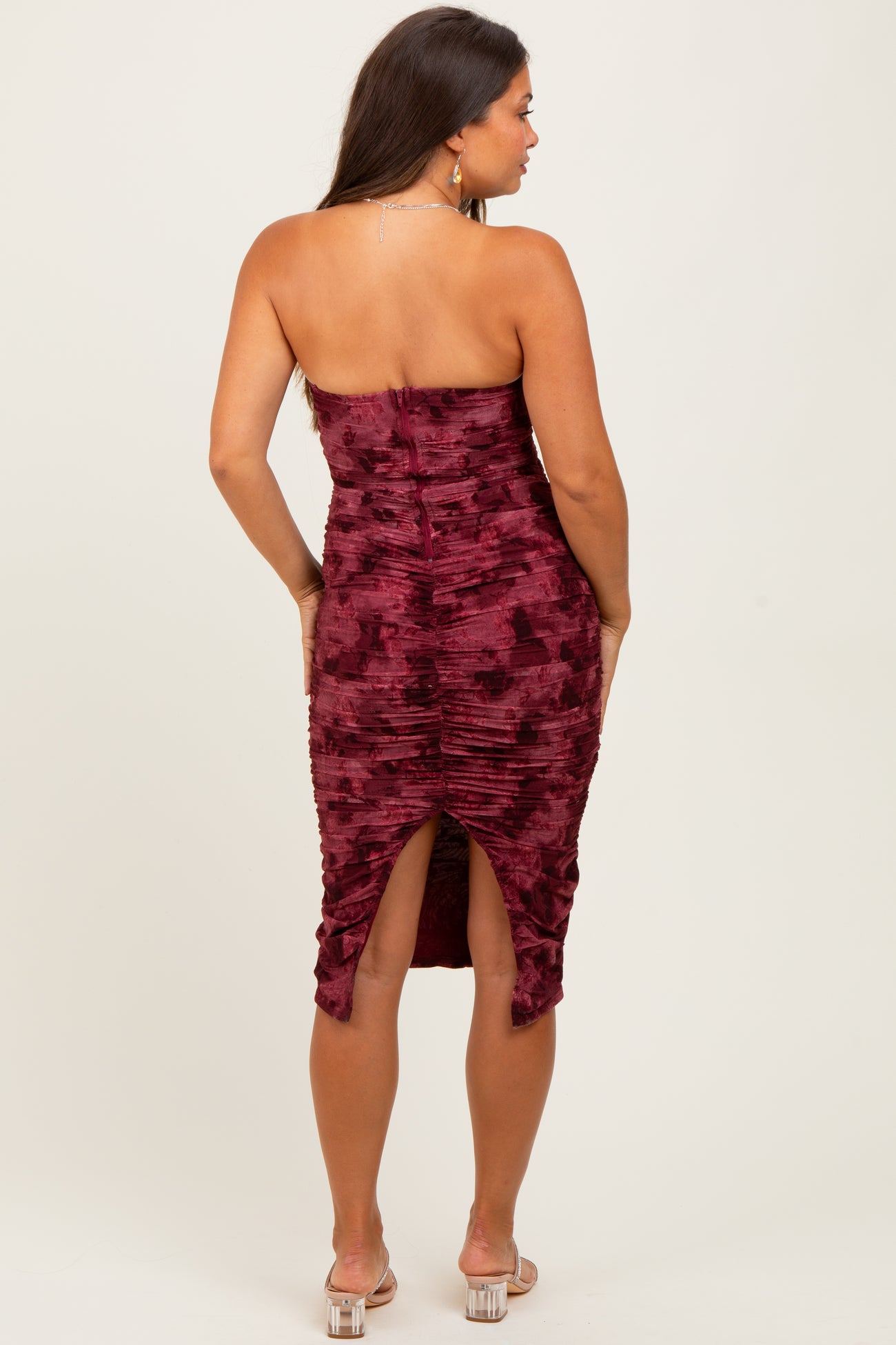 woman wearing a burgundy strapless maternity dress with ruching and a high slit in the back