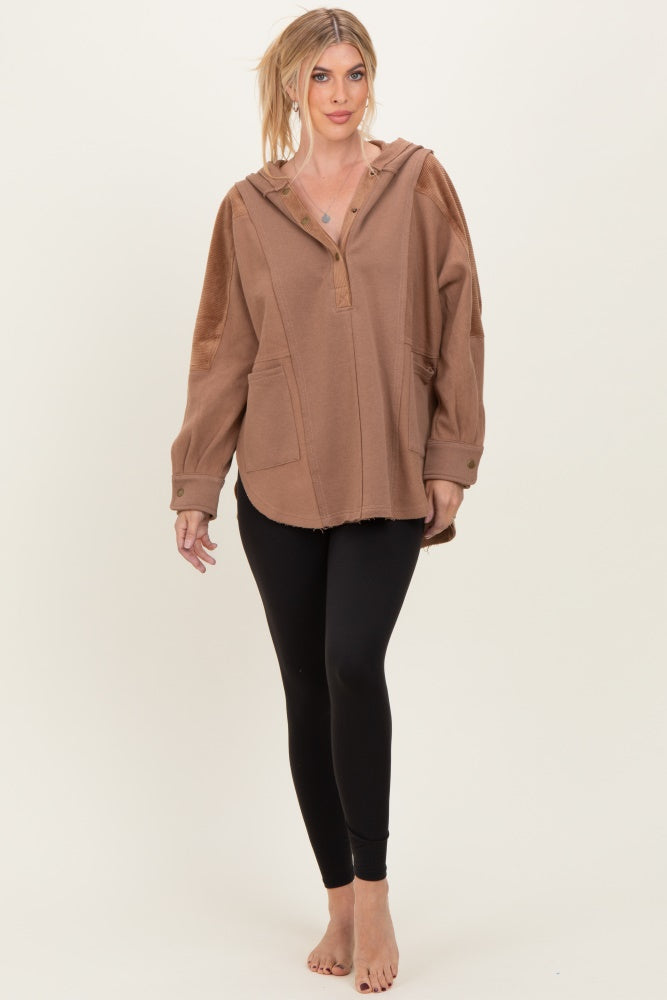 woman wearing a brown oversized hoodie with a hood and front pockets, paired with black leggings