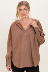 woman wearing a brown oversized hoodie with a button placket and side pockets, styled with black leggings
