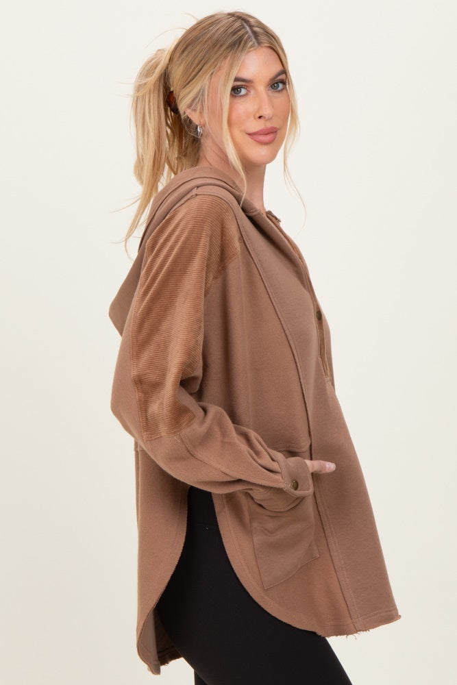 woman wearing a brown oversized hoodie with a front button and side pockets, model styled with loose waves in hair