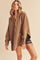 woman wearing a brown oversized hoodie with a front zipper and long sleeves over black distressed shorts