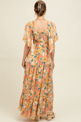 woman wearing a floral maternity maxi dress with short flutter sleeves and a smocked back, showing a baby bump