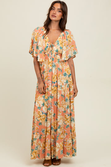 woman wearing a floral maxi dress with flutter sleeves in pink and yellow tones