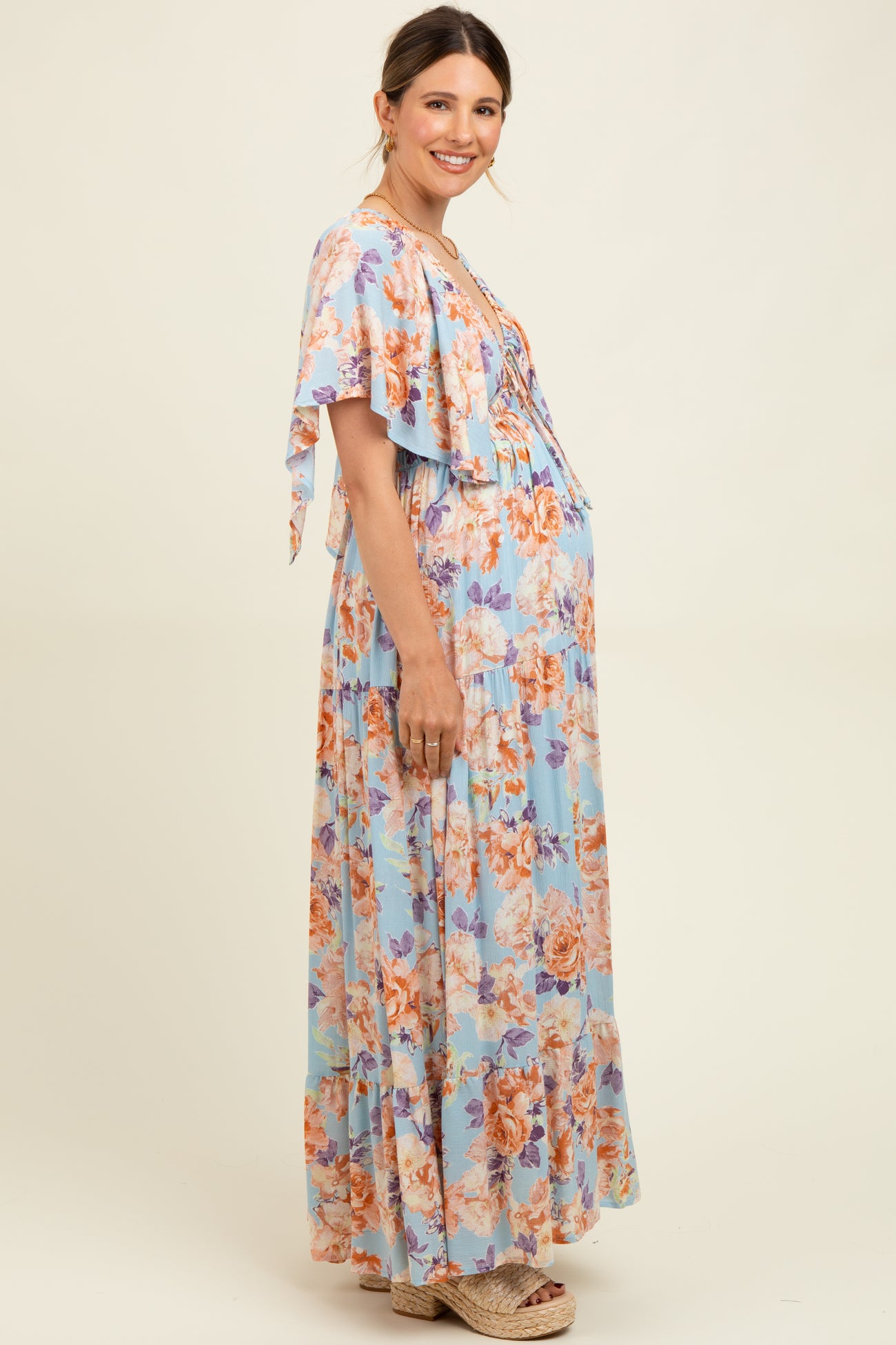 woman wearing a floral maternity maxi dress with flutter sleeves and a visible baby bump