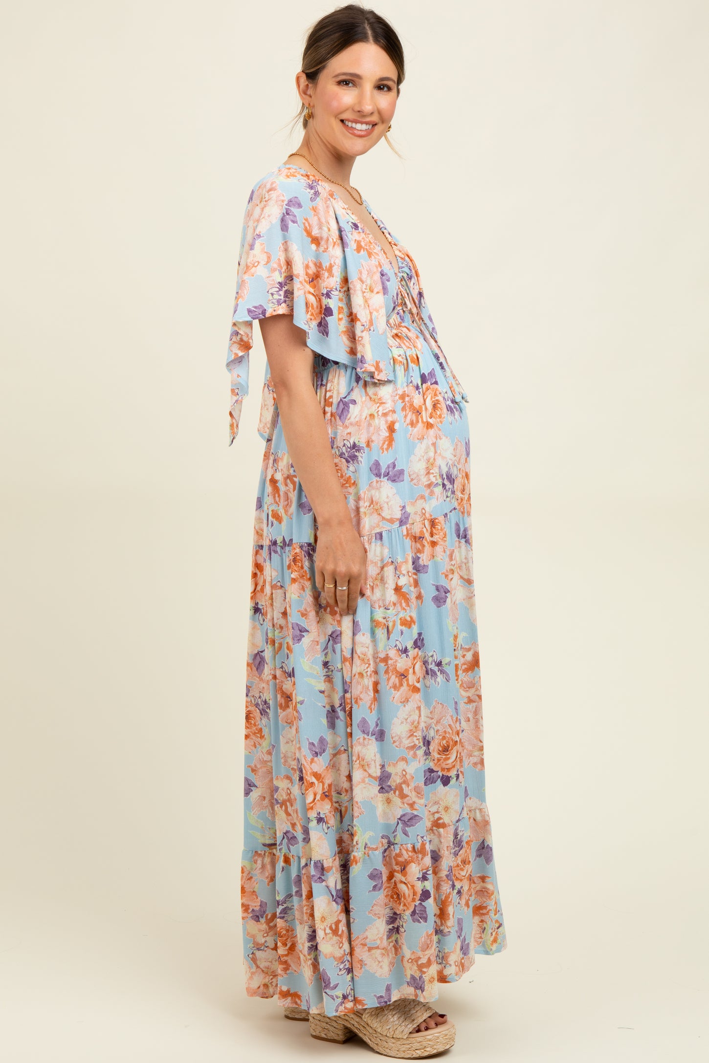 woman wearing a floral maternity maxi dress with flutter sleeves and a visible baby bump