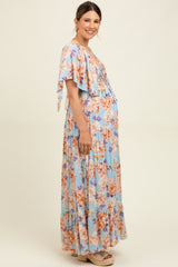 woman wearing a floral maternity maxi dress with flutter sleeves and a visible baby bump