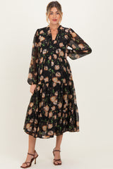 woman wearing a black floral maternity dress with long sleeves and a tiered skirt, showcasing a baby bump