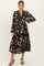 woman wearing a black floral maternity dress with long sleeves and a tiered skirt, showcasing a baby bump