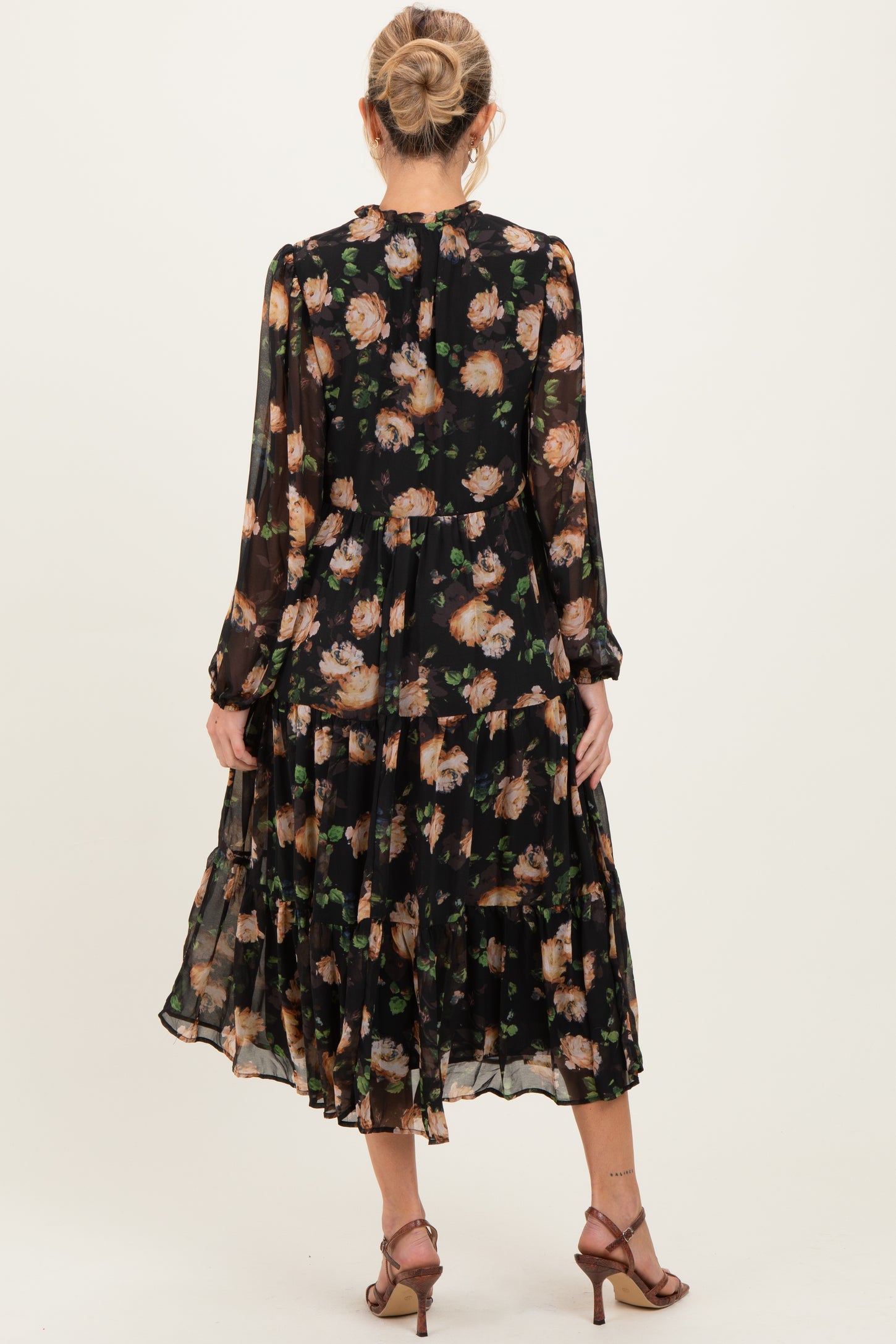 woman wearing a black floral long sleeve maternity dress with a tiered skirt, viewed from the back