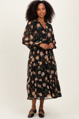 woman wearing a black floral maxi dress with long sleeves and a tiered skirt