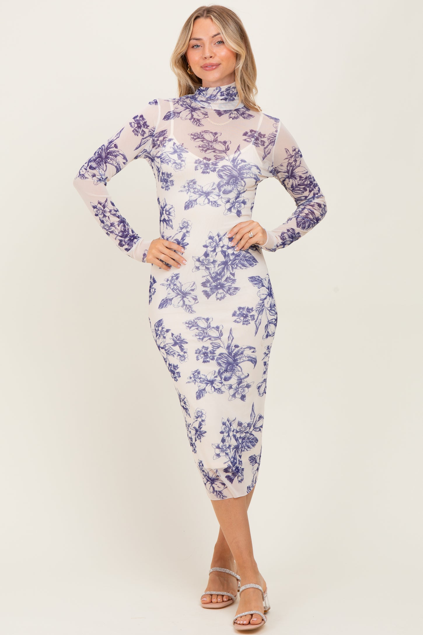 woman wearing a sheer long sleeve floral dress with a mock neck and fitted silhouette