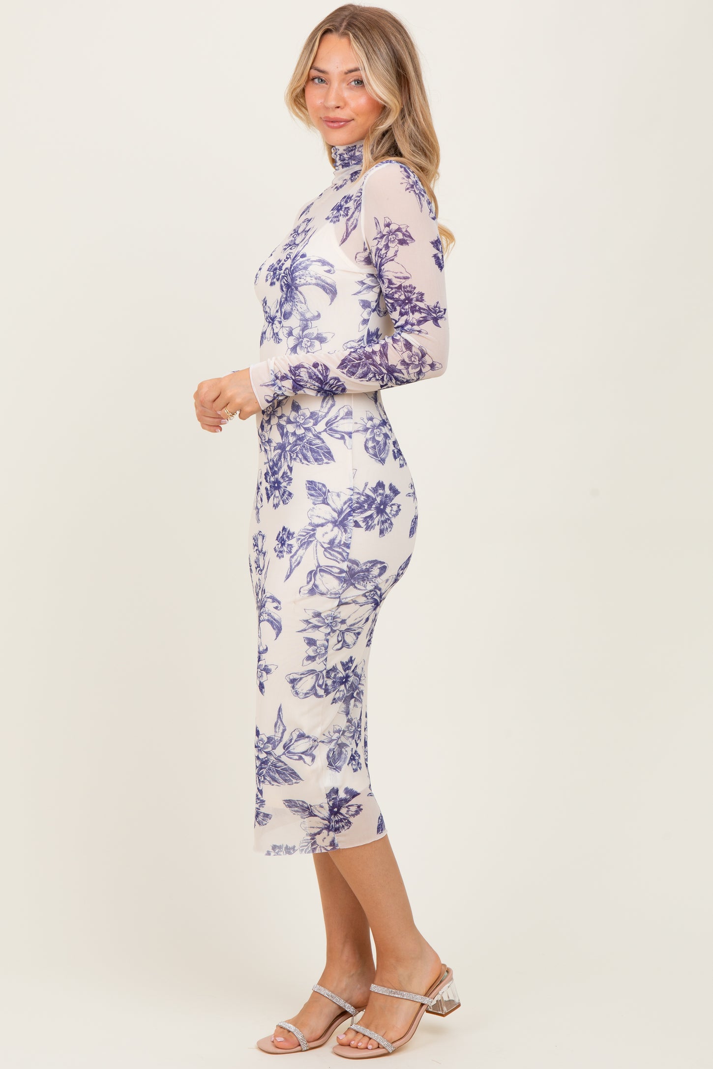 woman wearing a sheer long sleeve midi dress with blue floral print and a high neckline