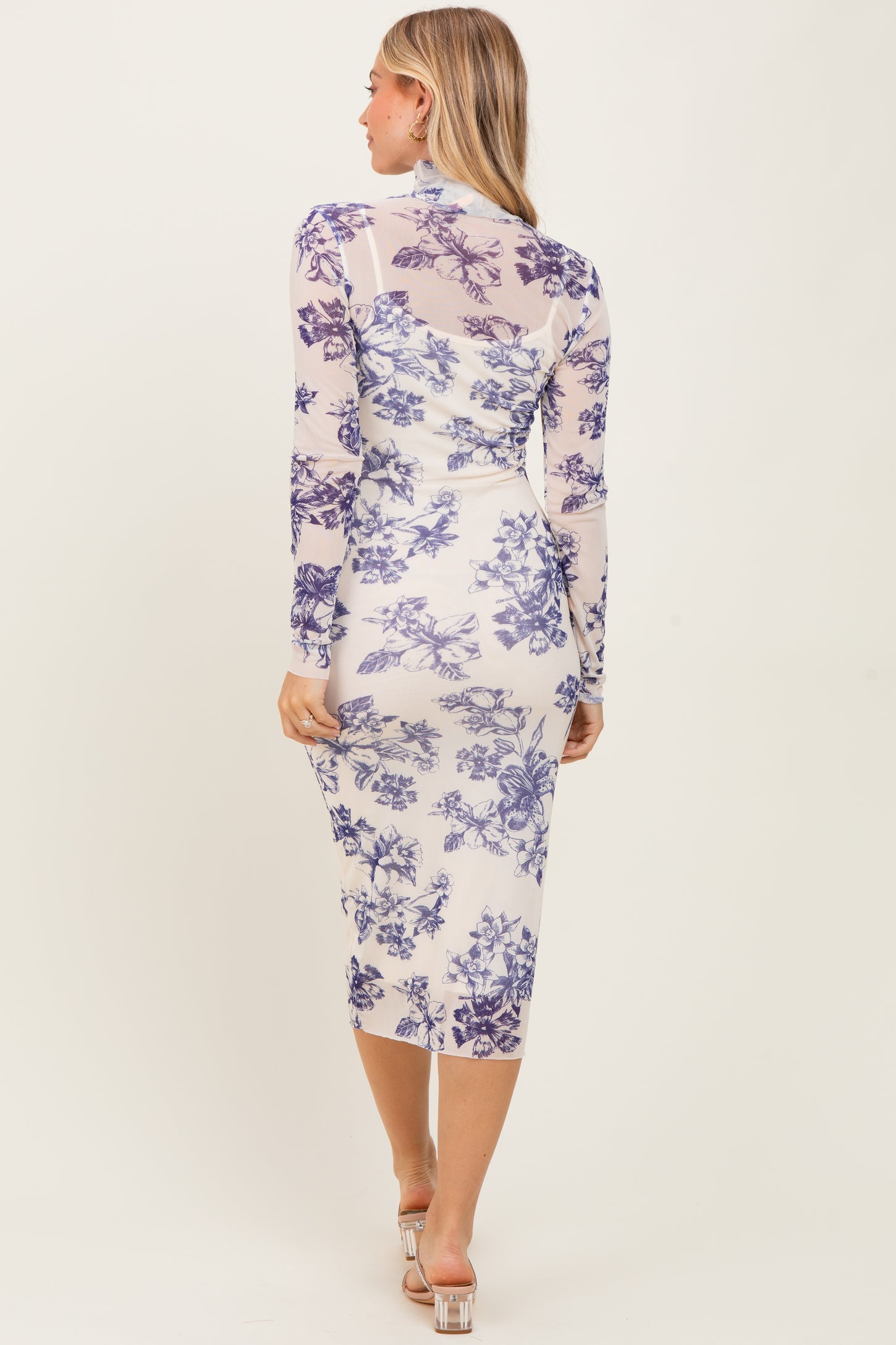 woman wearing a long sleeve bodycon dress with purple floral print and a midi length, shown from the back