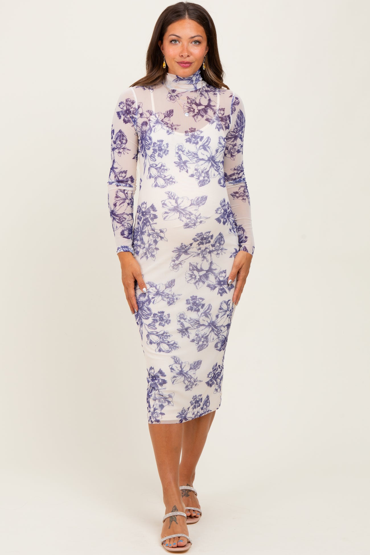 woman wearing a light purple floral print maternity dress with long sleeves and a high neckline, showing her baby bump