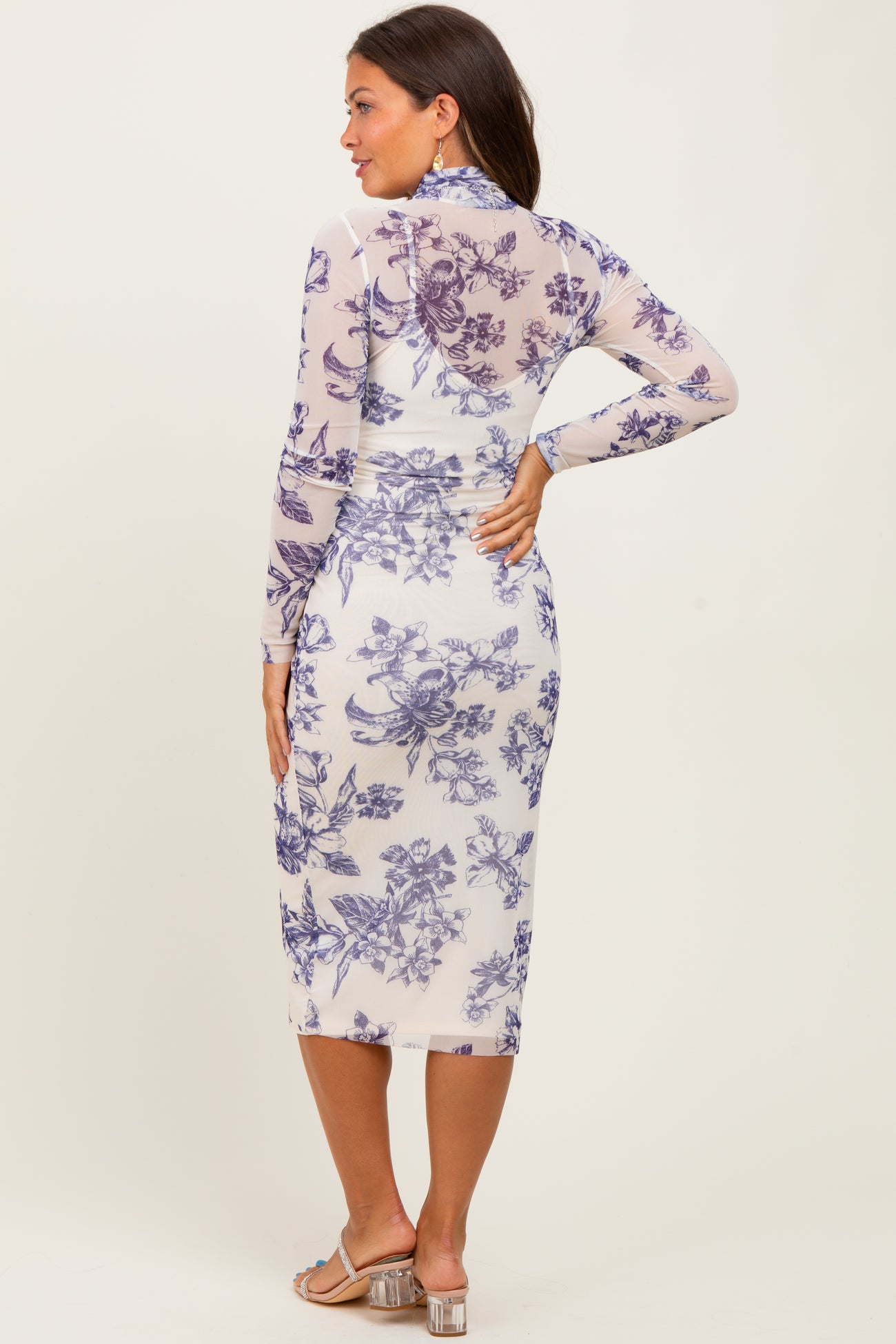 woman wearing a floral long sleeve maternity dress that hugs her baby bump, featuring a midi length and a form-fitting silhouette