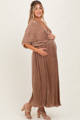 woman wearing a brown pleated maternity maxi dress and holding her baby bump
