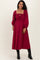 woman wearing a burgundy maternity dress with puff sleeves and a smocked bodice, styled with black knee-high boots