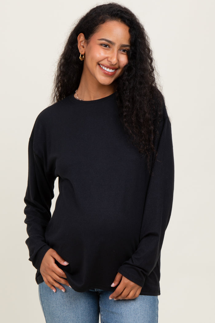 woman wearing a black long sleeve maternity top and showcasing her baby bump