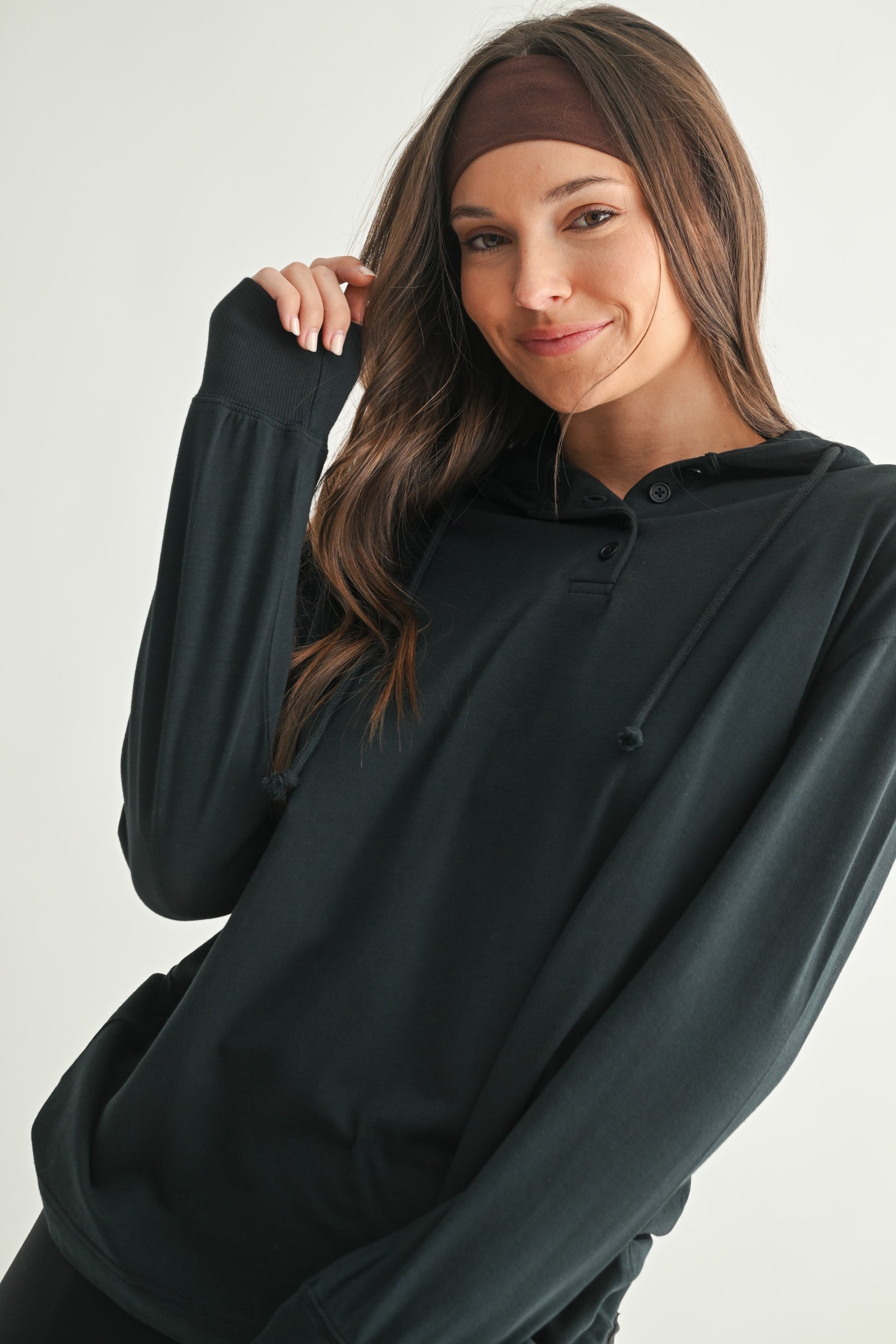 woman wearing a black long sleeve hooded top with buttons and drawstrings, smiling at the camera