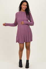 woman wearing a purple ribbed maternity dress with long sleeves and a flared skirt, holding her baby bump