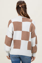 woman wearing a cream and brown checkered maternity sweater, showing the back view and styled with a ponytail