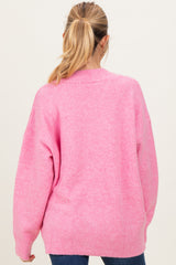 woman wearing a cozy pink oversized maternity sweater from the back