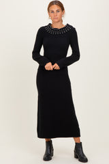 woman wearing a black long sleeve sweater dress with a decorative pearl collar and ankle boots
