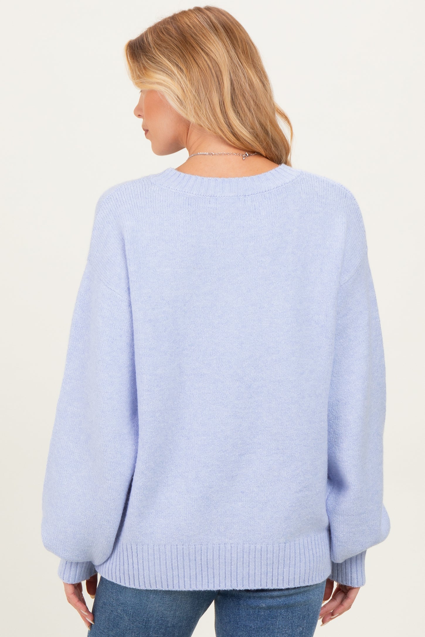 woman wearing a light purple oversized maternity sweater viewed from the back