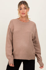 woman wearing a beige oversized maternity sweater with a relaxed fit and long sleeves, baby bump visible