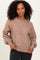 woman wearing a beige oversized sweater with balloon sleeves and a round neckline, styled with black jeans