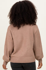 woman wearing a beige oversized sweater with balloon sleeves and a ribbed hem, viewed from the back