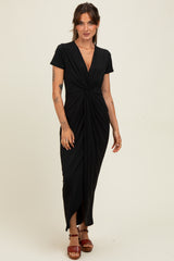 woman wearing a black short sleeve maxi dress with a twisted front detail and a side slit